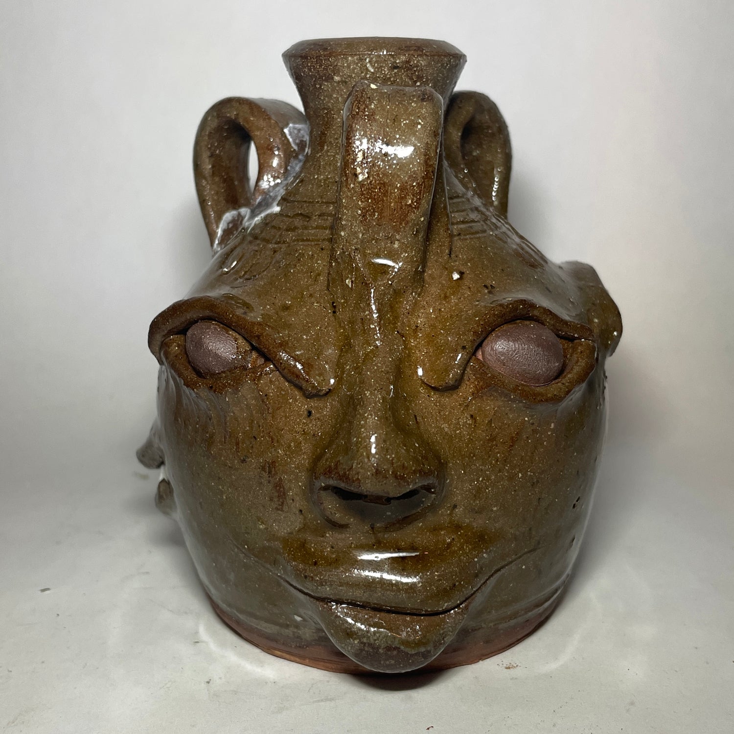 Face 2 of triple face jug.  Brown clay, clear glaze.