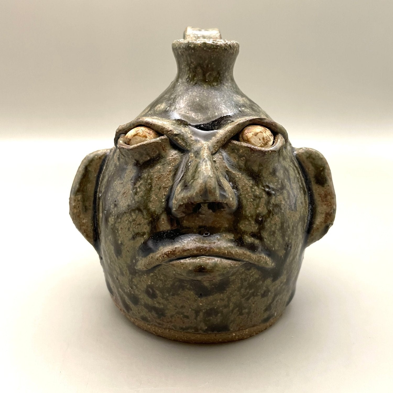 Folk art face jug with green ash glaze